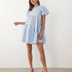 robes bleu ciel à pois crépon bouffantes courte asymétrique cordon serrage manches portee par un mannequin sur fond blanc