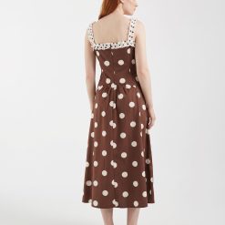 robes mousseline à pois bretelles noué détail longueur mollet marron avec des pois blancs sur un mannequin posant dos à lappareil en intérieur