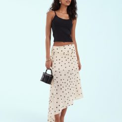 jupes à pois ivoire fente sur côté asymétrique portée avec un caraco noir et un petit sac main