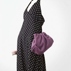 robes longues noires à pois dos nu lynette portée avec un sac pochette violet et des bracelets élégants