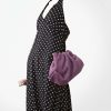 robes longues noires à pois dos nu lynette portée avec un sac pochette violet et des bracelets élégants