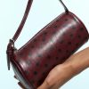 sacs à main à pois polochon bordeaux en cuir effet brillant imprime de motifs pois noirs avec une anse et une fermeture a glissiere argentee