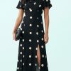 robes évasées à pois manches col bénitier oversize fendue noirs portée par un mannequin avec une petite pochette noire