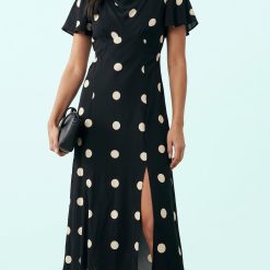 robes évasées à pois manches col bénitier oversize fendue noirs portée par un mannequin avec une petite pochette noire