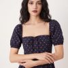 robes à pois transparentes encolure carrée manches bouffantes longueur mollet bleu marine roses portée par une femme aux cheveux sombres avec un noeud sur le devant du buste
