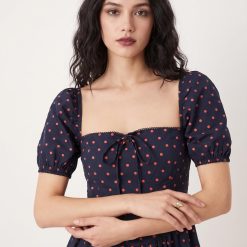 robes à pois transparentes encolure carrée manches bouffantes longueur mollet bleu marine roses portée par une femme aux cheveux sombres avec un noeud sur le devant du buste