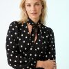 robes longues noires à pois blancs sadie col lavallière longueur mollet portée par une mannequin blonde aux cheveux ondulés avec manches longues