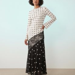 robes longues noires à pois monochrome dentelle avec bordures en satin portée par une mannequin à manches longues sur fond bleu clair
