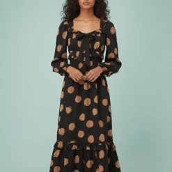 robes longues marron à pois bardot encolure avec nœud longueur mollet portée par un mannequin femme aux cheveux bruns robe noire imprimée de pois marron avec manches longues bouffantes