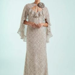 robes longues marron à pois crème et fines col cape fleur bretelles v détail élégante robe de soirée avec cape intégrée et fleur tissu sur le col portee par un mannequin