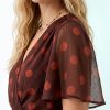 robes longues à pois rouge cerise portefeuille manches ange surpiqûres en tissu marron fluide porté par une femme