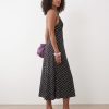robes longues noires à pois dos nu lynette portée par une femme aux cheveux bouclés avec des sandales noires