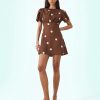 robes longues marron à pois et manches courtes portée par une mannequin avec des sandales marron sur un fond bleu clair