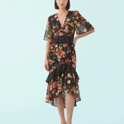 robes longues noires à pois fleurs basque imprimé taille haute avec col en v manches evasees et jupe a volants asymetrique motif floral multicolore sur mannequin