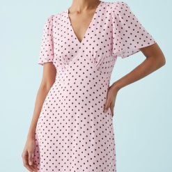 robes évasées à pois manches courtes col v rose marron imprimée de motifs bordeaux ajustée à la taille et portée par un mannequin avec des boucles d oreilles dorées