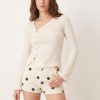 shorts à pois écru imprimé en jean taille haute court porté par un mannequin femme associé à un top écru ajusté à manches longues