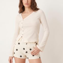 shorts à pois écru imprimé en jean taille haute court porté par un mannequin femme associé à un top écru ajusté à manches longues