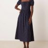 robes à pois transparentes encolure carrée manches bouffantes longueur mollet bleu marine roses portée par une femme avec des chaussures grises sur fond neutre
