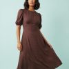 robes longues marron à pois marianna encolure bateau manches bouffantes coupe evasee mi longue portee par une femme avec bottes noires