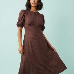robes longues marron à pois marianna encolure bateau manches bouffantes coupe evasee mi longue portee par une femme avec bottes noires